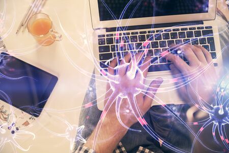 Double exposure of mans hands typing over computer keyboard and neuron hologram drawing. Top view....