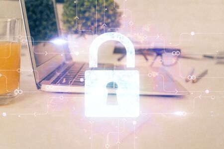 Double exposure of desktop with computer and lock icon hologram. Concept of data safety.