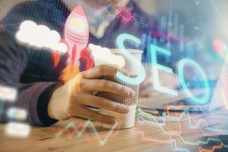 Multi exposure of seo icon with man working on computer on background. Concept of search engine optimization.の写真素材