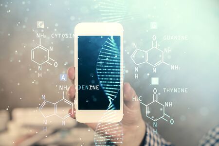 Double exposure of mans hands holding and using a phone and DNA drawing. Medical education concept.の写真素材