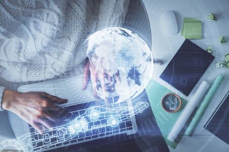 Double exposure of woman hands working on computer and world map hologram drawing. Top View. International business concept.の写真素材