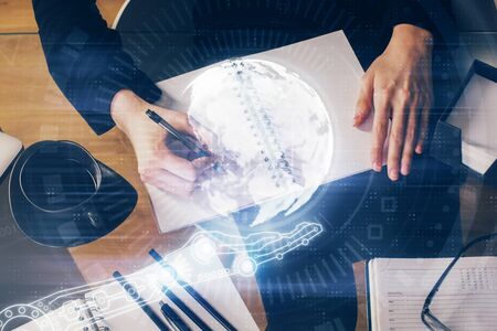 Double exposure of hands making notes with world map hologram and data theme icons. Concept of global computer data.の写真素材