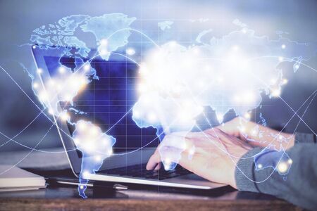 Multi exposure of businessman working on laptop on background. International business hologram in...