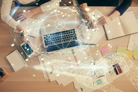 Double exposure of woman hands working on computer and social network theme hologram drawing. Top...
