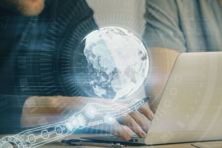 Double exposure of world map hologram with man working on computer on background. Concept of worldwideweb.の写真素材