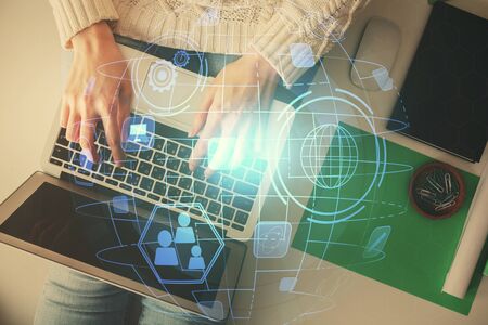 Double exposure of woman hands working on computer and social network theme hologram drawing. Top...