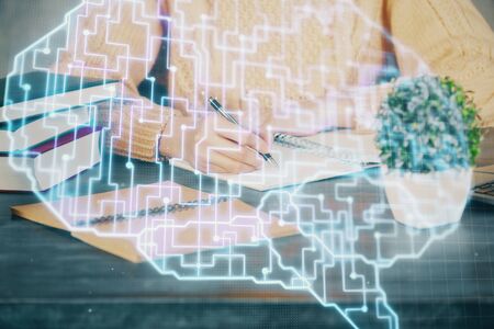 Multi exposure of writing hand on background with brain hologram. Concept of learning.の写真素材