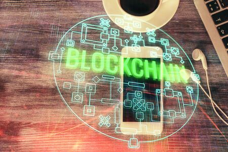 Double exposure of blockchain theme hologram over table with phone. Top view. Crypto technology concept.の写真素材