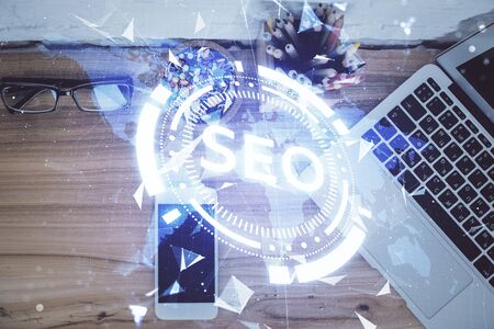 Double exposure of SEO hologram drawing over desktop. Top view. Search optimization concept.の写真素材
