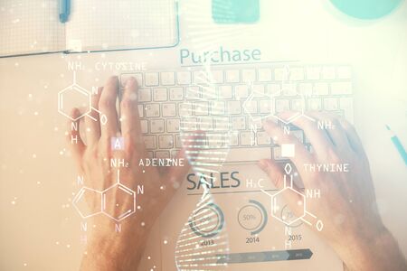 Double exposure of mans hands typing over computer keyboard and DNA hologram drawing. Top view. Medical education concept.の写真素材