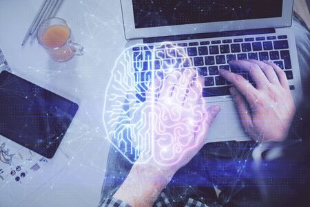 Double exposure of man's hands typing over computer keyboard and brain hologram drawing. Top view....