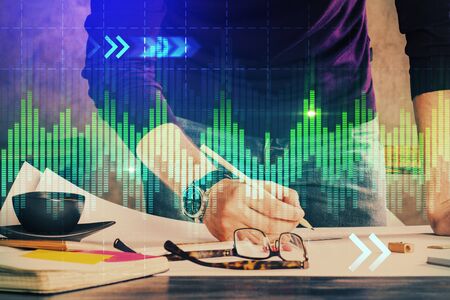 Double exposure of man writing on paper with forex graph. Concept of research and trading.