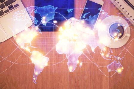Double exposure of business theme hologram over desktop with phone. Top view. Mobile international...