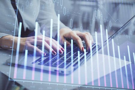 Multi exposure of woman hands typing on computer and financial graph hologram drawing. Stock market analysis concept.の写真素材