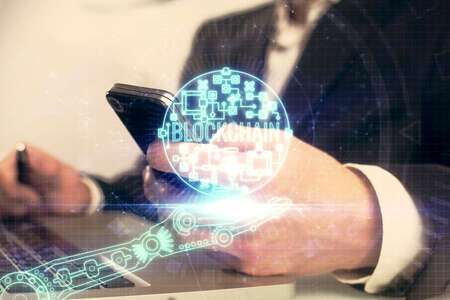 Double exposure of mans hands holding and using a phone and crypto currency blockchain theme...