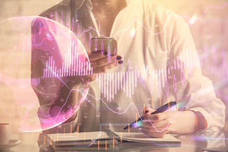 Double exposure of financial graph sketch hologram and woman holding and using a mobile device....