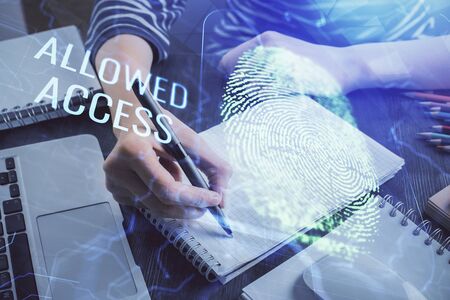 Blue fingerprint hologram over hands taking notes background. Concept of security. Double exposureの写真素材