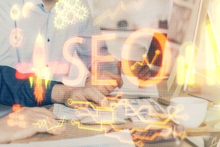Multi exposure of seo icon with man working on computer on background. Concept of search engine optimization.の写真素材