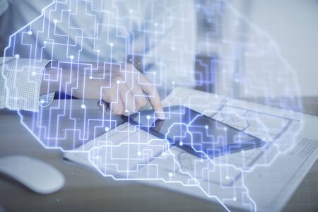 Double exposure of mans hand holding and using a digital device and brain hologram drawing. Data...