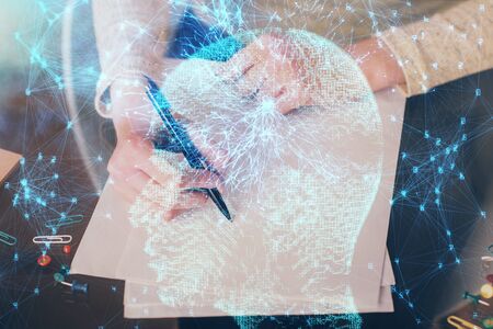 Double exposure of writing hand on background with brain hologram. Concept of learning.