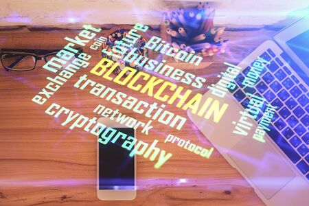 Double exposure of blockchain theme hologram over table with phone. Top view. Crypto technology...