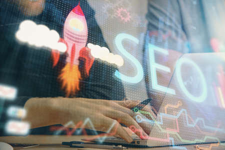 Multi exposure of seo icon with man working on computer on background. Concept of search engine optimization.の写真素材