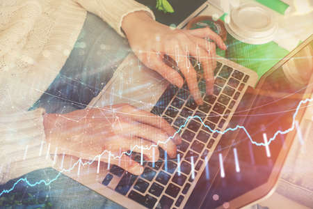 Double exposure of woman hands typing on computer and forex chart hologram drawing. Stock market...