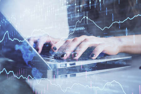 Double exposure of woman hands typing on computer and forex chart hologram drawing. Stock market...