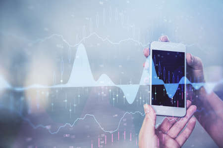 Double exposure of forex graph sketch hologram and woman holding and using a mobile device. Stock...