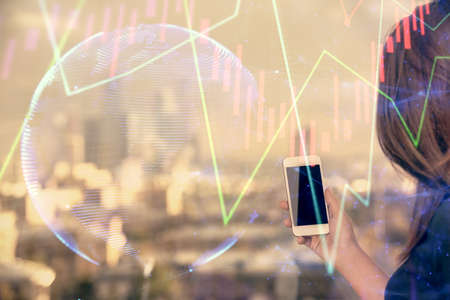 Double exposure of forex chart sketch hologram and woman holding and using a mobile device. Stock...