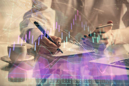 Double exposure of financial graph sketch hologram and woman holding and using a mobile device....
