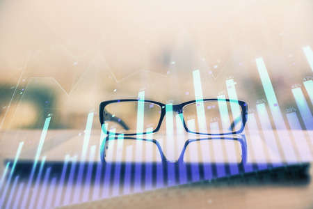 Financial graph hologram with glasses on the table background. Concept of business. Double exposure.の写真素材