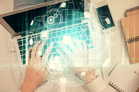 Double exposure of woman hands working on computer and social network theme hologram drawing. Top...