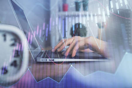 Double exposure of woman hands typing on computer and forex chart hologram drawing. Stock market...
