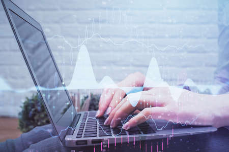 Multi exposure of woman hands typing on computer and forex chart hologram drawing. Stock market...