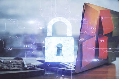 Double exposure of desktop with computer and lock icon hologram. Concept of data safety.