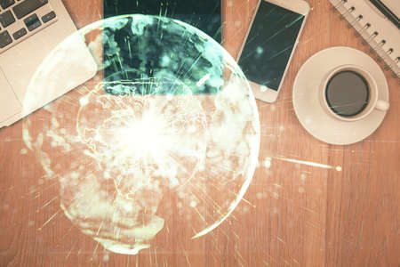 Double exposure of business theme hologram over desktop with phone. Top view. Mobile international trade connection concept.の写真素材