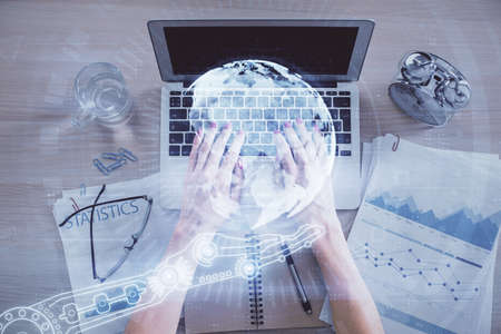 Double exposure of woman hands working on computer and world map hologram drawing. Top View....