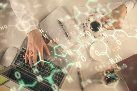 Double exposure of mans hands typing over computer keyboard and formula hologram drawing. Top view. Education concept.の写真素材