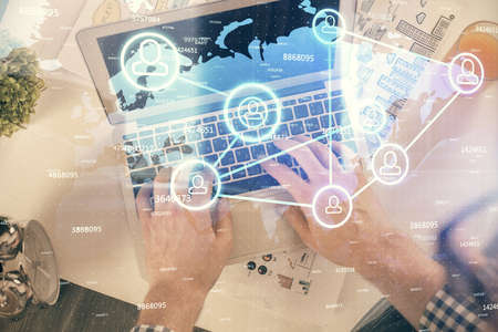 Double exposure of mans hands typing over computer keyboard and social network theme hologram...
