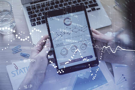 Double exposure of mans hand holding and using a digital device and data theme hologram drawing. Technology concept.の写真素材