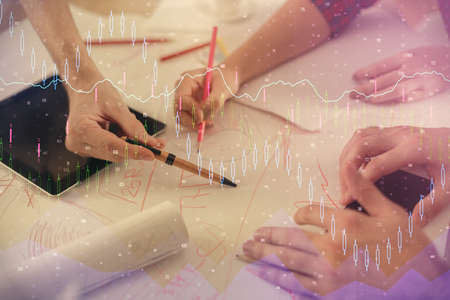 Double exposure of forex graph drawing and man and woman working together holding and using a mobile device. Trade concept.の写真素材