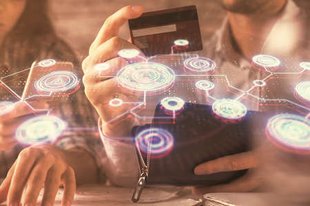 Double exposure of man and woman on-line shopping holding a credit card and social network theme hologram drawing. People connecting and E-commerce pay on-line concept.の写真素材