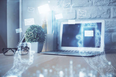 Desktop computer background in office and flying envelops hologram drawing. Multi exposure. Electronic mail concept.の写真素材