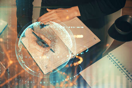 Double exposure of hands making notes with world map hologram and data theme icons. Concept of...