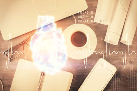 Heart hologram drawings over computer on the desktop background. Top view. Multi exposure. Concept of medical education.の写真素材
