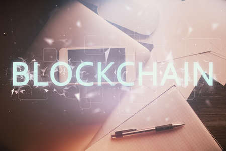 Double exposure of blockchain theme hologram over table with phone. Top view. Crypto technology concept.の写真素材