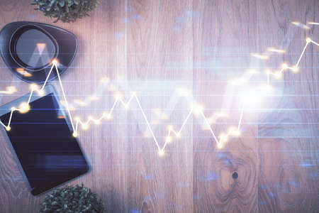 Multi exposure of financial chart hologram over desktop with phone. Top view. Mobile trade platform...