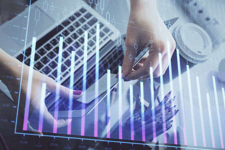 Double exposure of businesswoman hands typing on computer and financial graph hologram drawing....