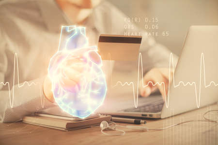 Double exposure of man hands holding a credit card and human heart drawing. Medical education and E-commerce concept.の写真素材